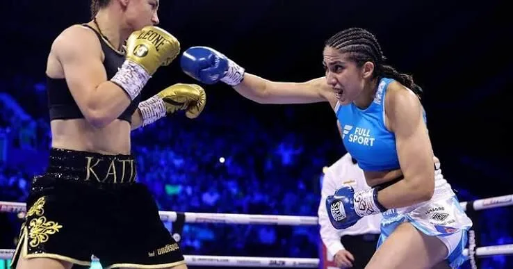 María Laura Carabajal con guantes de boxeo posando en ring con bandera argentina