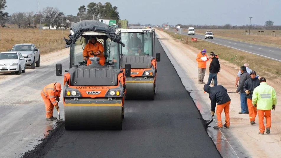 Camión circulando por una ruta nacional pavimentada con carteles de concesión al fondo