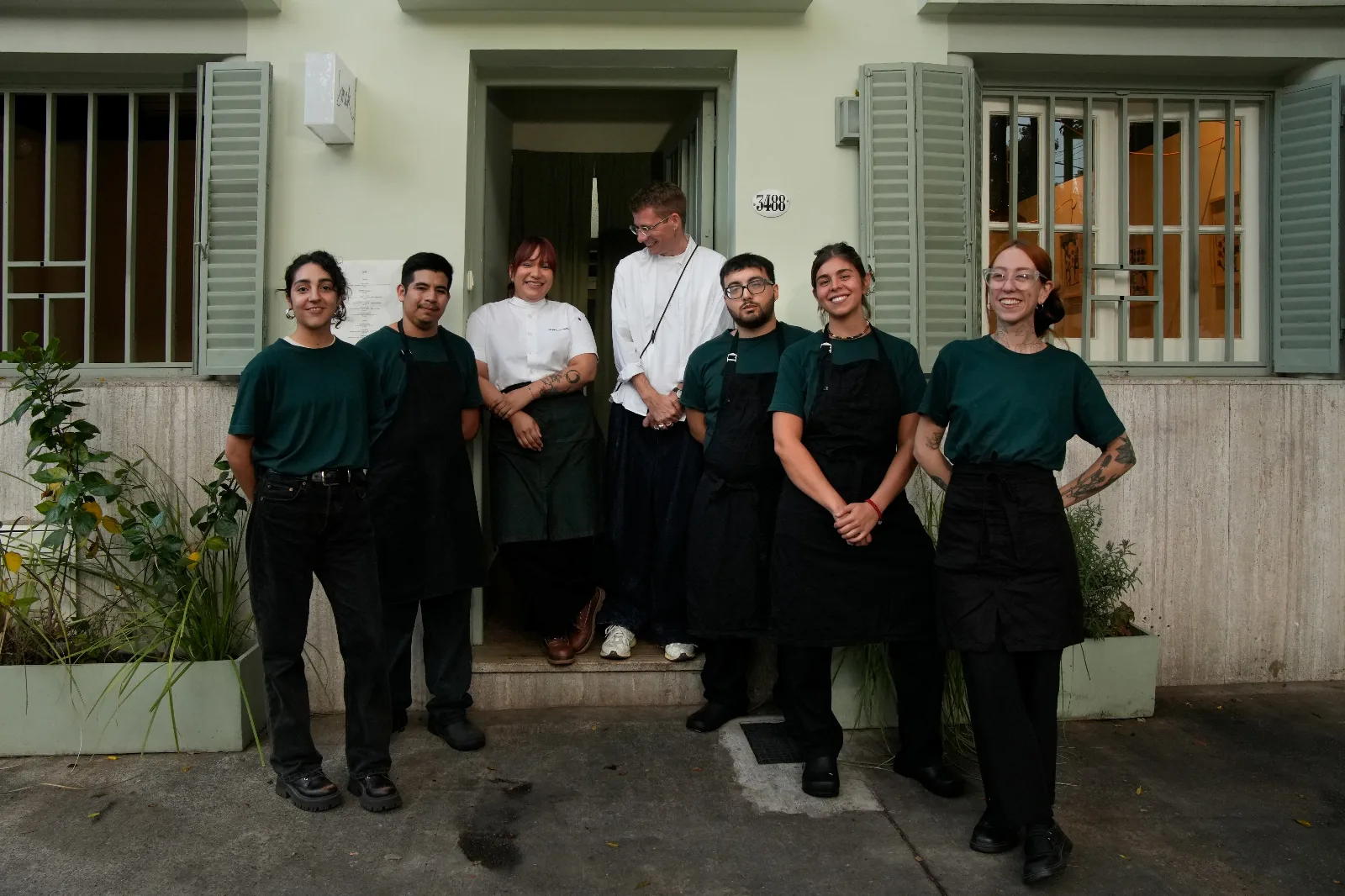 Fachada moderna de un café con mesas en la vereda en una calle arbolada de Colegiales