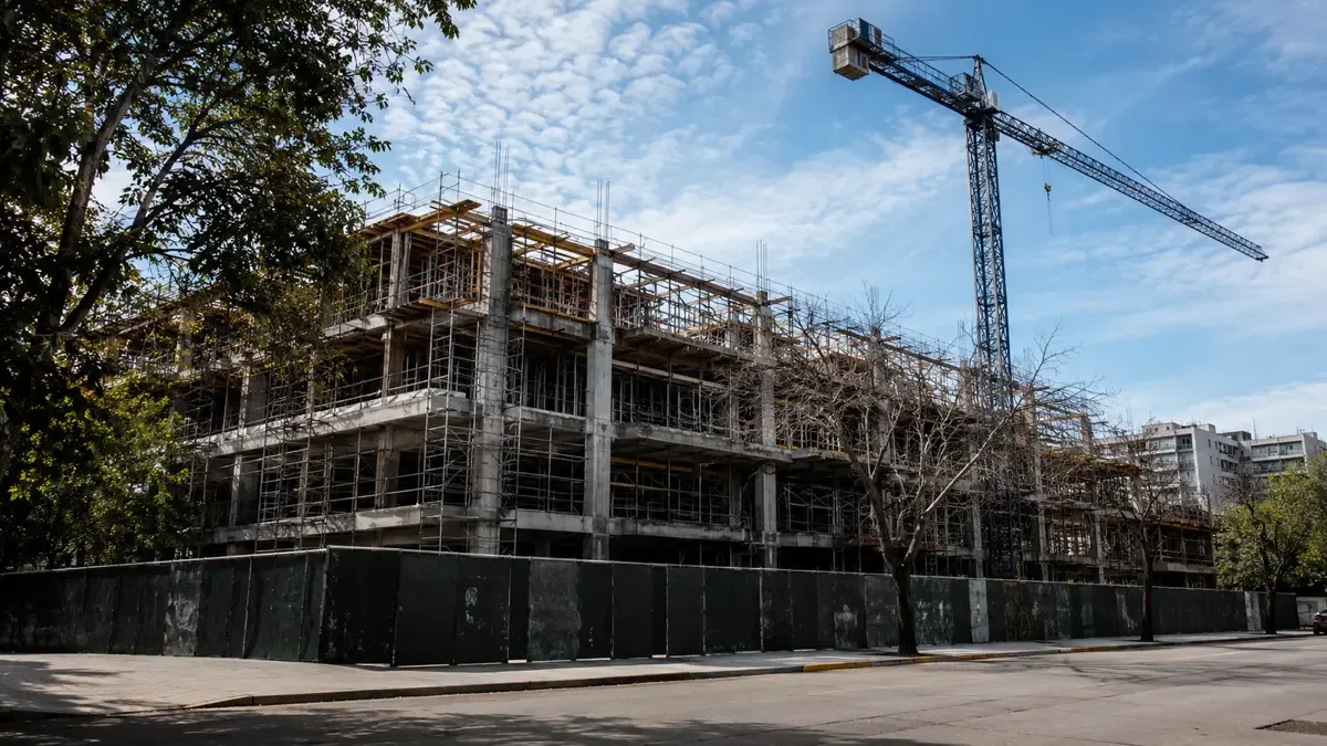 Obra en construccion con andamios y una grua recortada contra el cielo