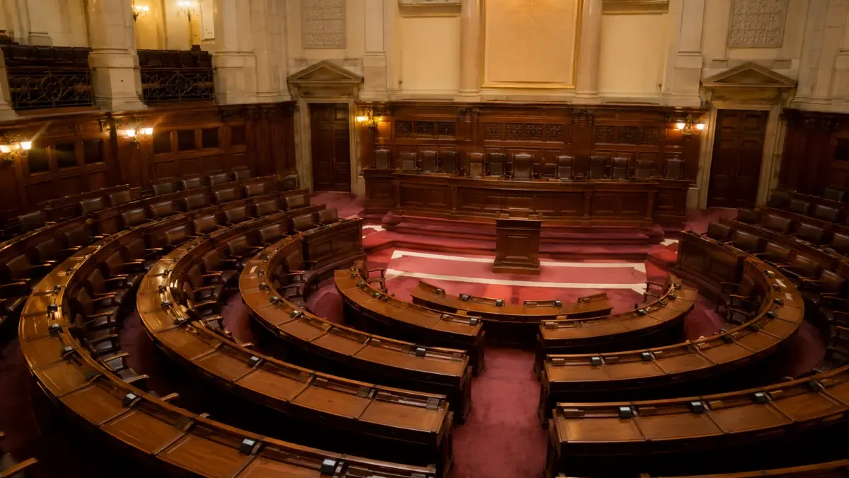 Recinto legislativo con bancas de madera vacías en semicírculo