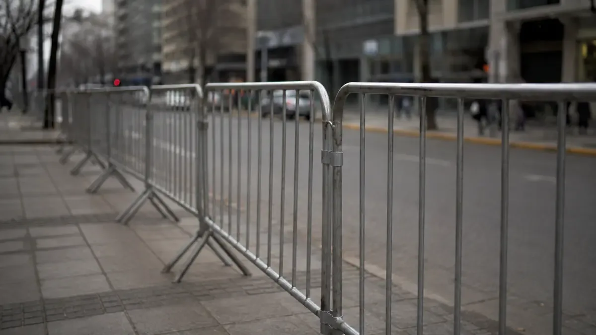Vallado metalico de evento en una vereda con la calle desenfocada al fondo