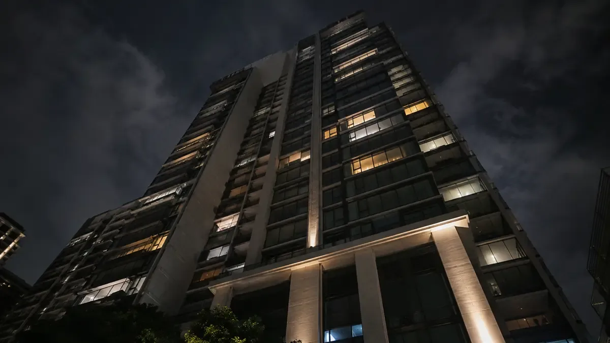 Fachada de una torre de departamentos de lujo con ventanales iluminados en una noche urbana