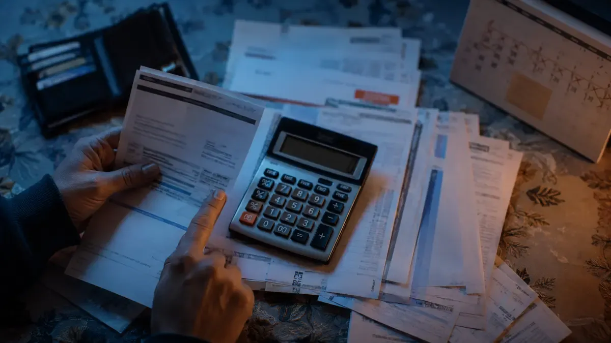 Mano con calculadora sobre un resumen de tarjeta mientras varias cuotas se acumulan en un calendario
