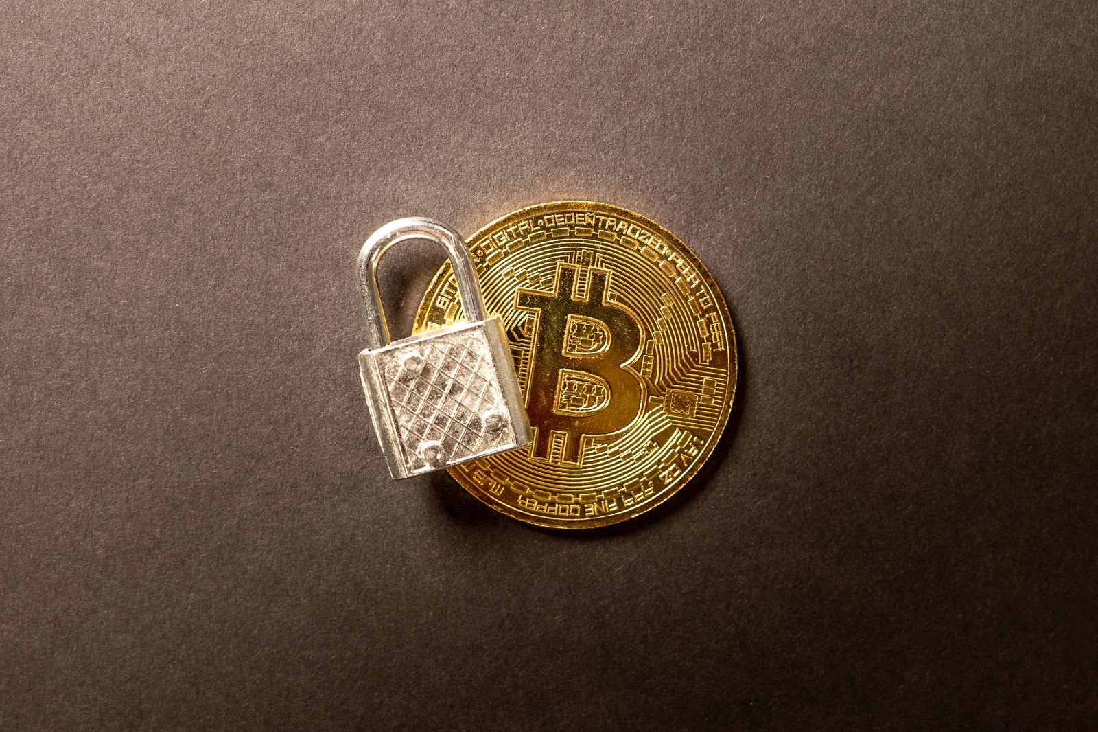 Candado metalico sobre una moneda de Bitcoin, representando la seguridad y el cifrado de activos digitales