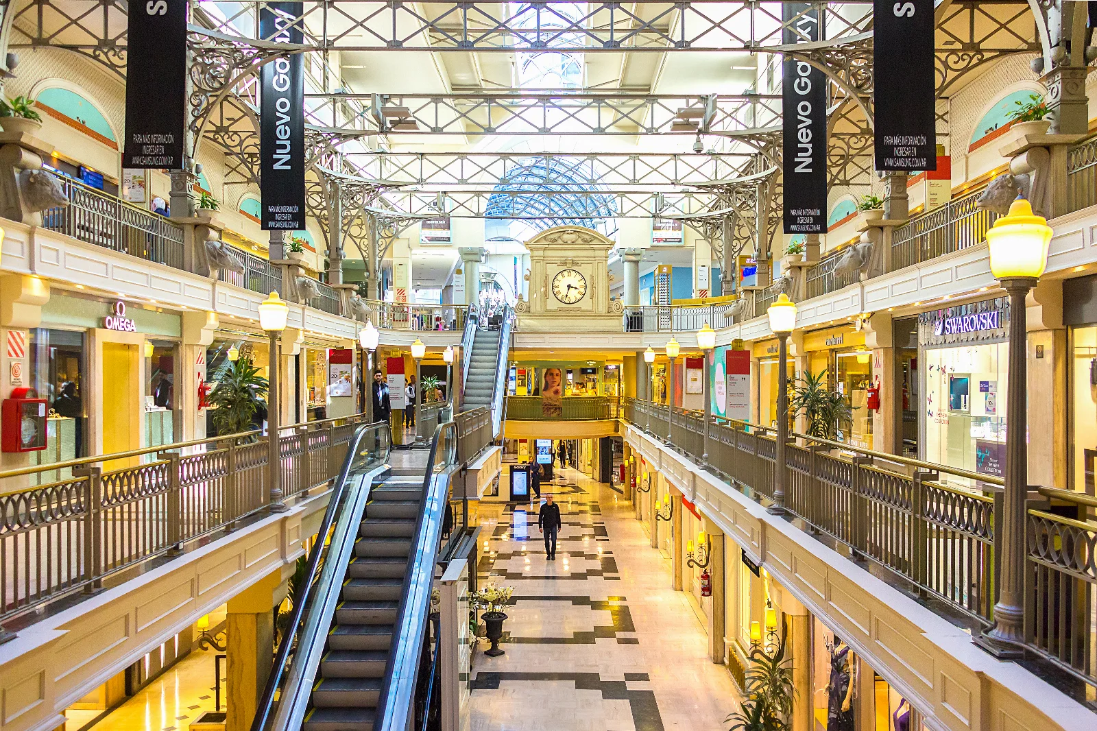 Fachada moderna del shopping Alto Palermo con vidrieras de lujo y clientes entrando